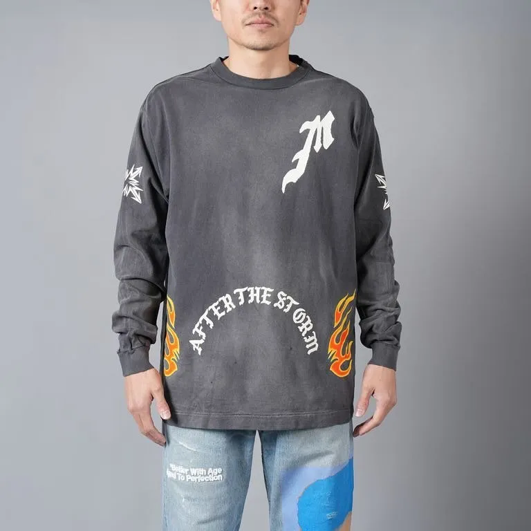 SAINT Mxxxxxx M/AFTER LS_TEE/BLACK Flame arrow Letter M retro distressed long tee Washed black S-XL Tubular fabric Assute ready-made garments dyed The whole piece is sprayed with horse-hair spray and then sprayed again to fade the color. The collar and cuffs are frayed. Many places are frayed. Extra large printing position. Very difficult to print. Complete accessories. With little angel anti-counterfeiting label.